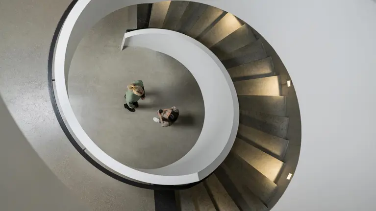 A spiral staircase leading to two students talking top view