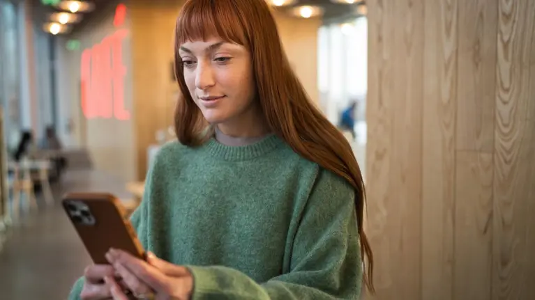 A young red hair woman using her phone in a cafe
