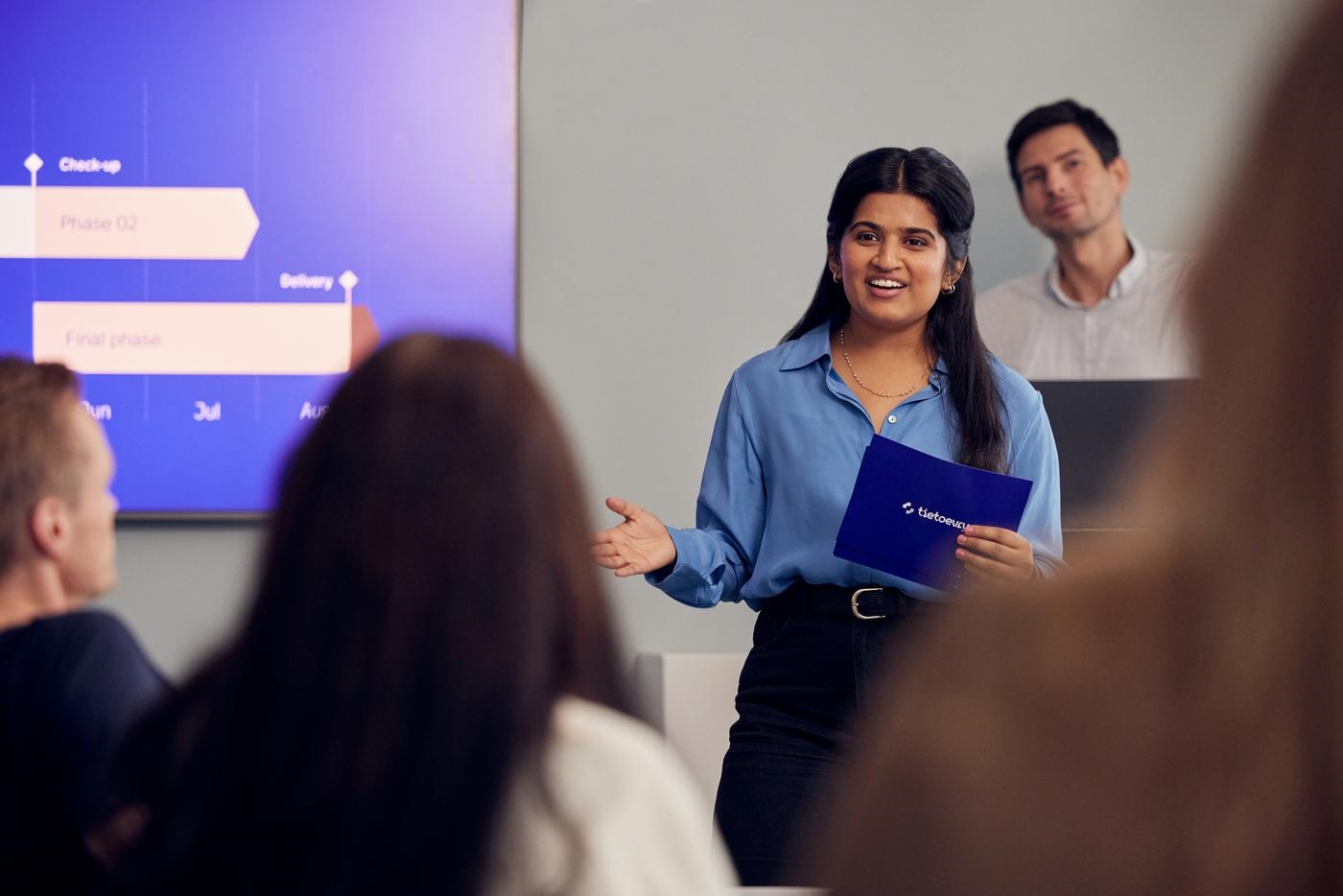 Woman presenting timeline in a meeting holding a card