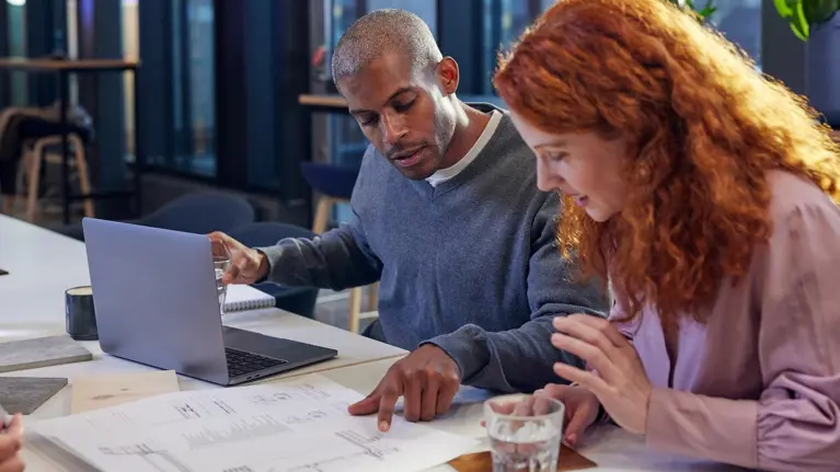man and woman looking at blueprints at table