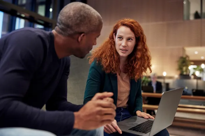 Man and woman co-working. holding laptop.