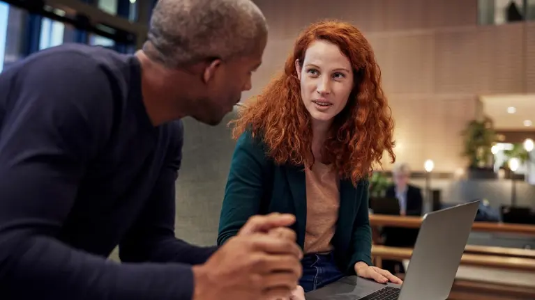 Man and woman co-working. holding laptop.