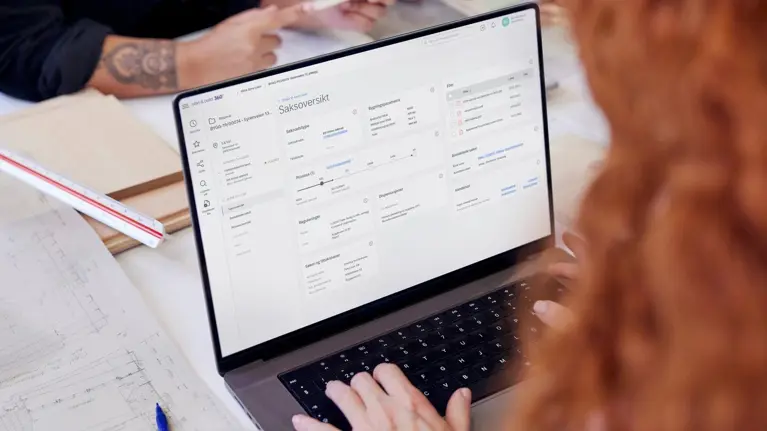 a person working on laptop with Public 360. Blueprints on the table