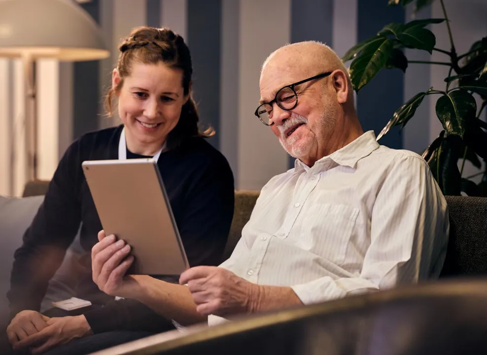 Social worker and an elderly man looking at tablet
