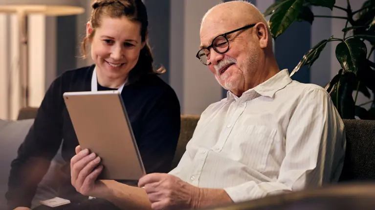 Social worker and an elderly man looking at tablet