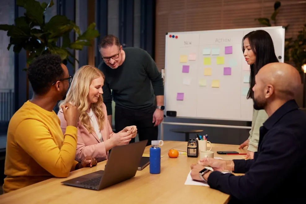 Men and women in a collaboration meeting working together using sticky notes and white board