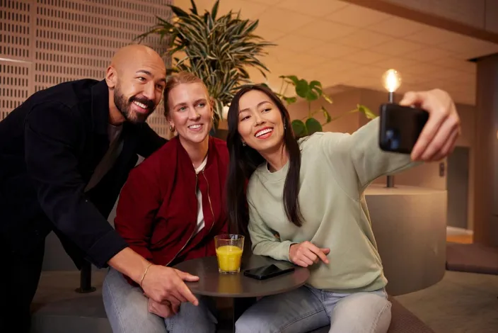 Team mates and colleagues taking a selfie photo with a cell phone smiling