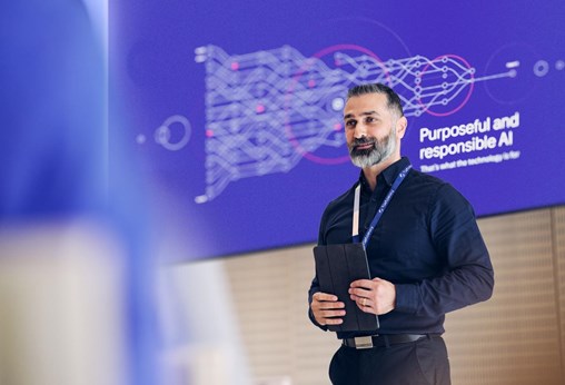 A Tietoevry employee giving a speech about Ai with Purposeful Ai message on the screen behind him