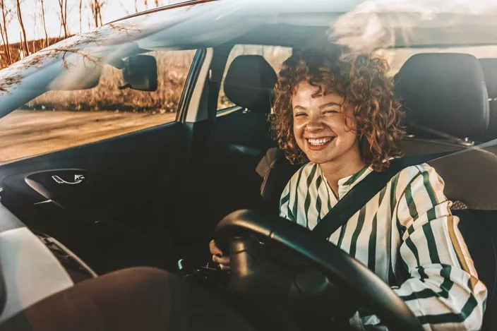 Young woman driving a car, smiling