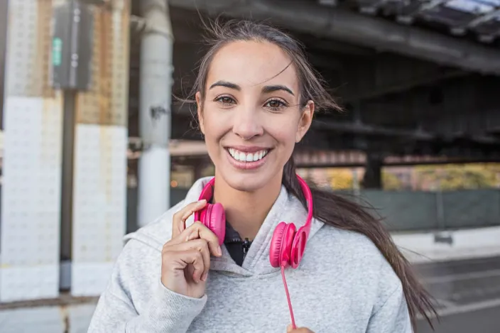 Portrait of smiling young athlete with headphones. Confident fit woman is wearing sportswear.