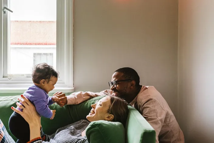 Parents with baby girl sitting on sofa at home
