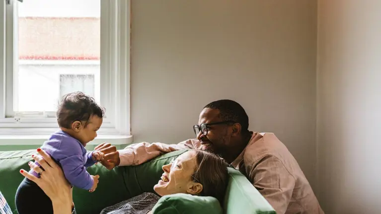 Parents with baby girl sitting on sofa at home