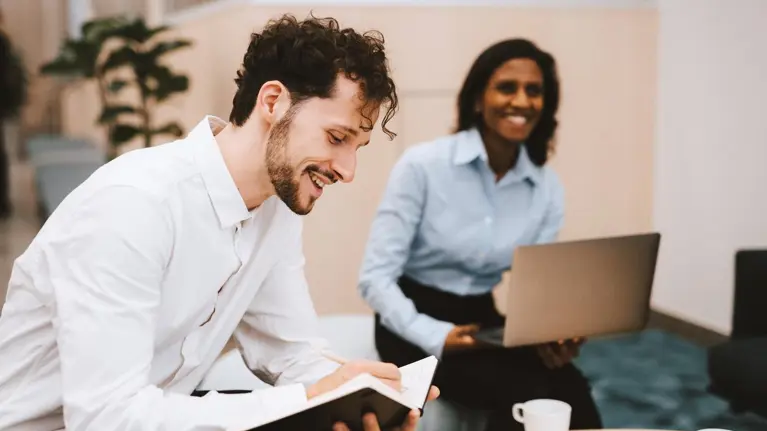 two people sitting in a meeting and smiling