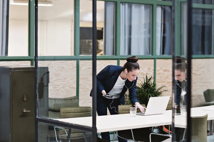 Woman talking on cellphone in headset and using laptop