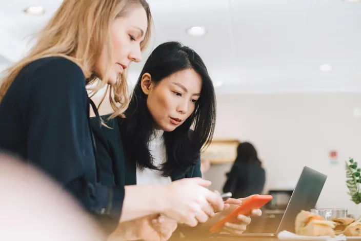 Colleagues use mobile phones during conferences in offices