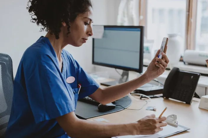 Doctor using a phone, giving patient an online consultation