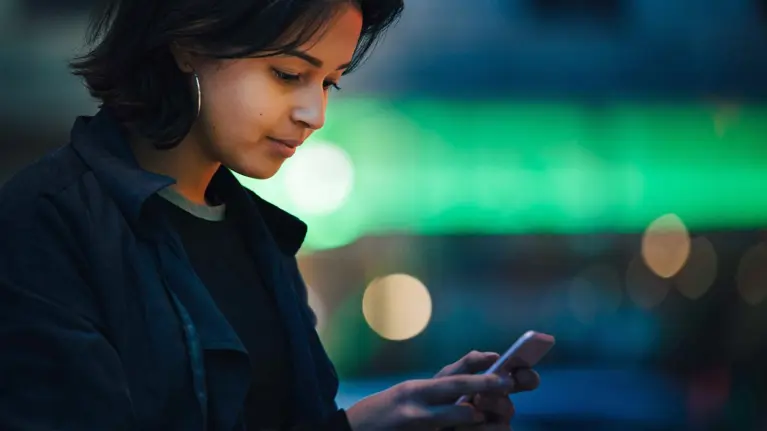 A young woman is using her phone smiling