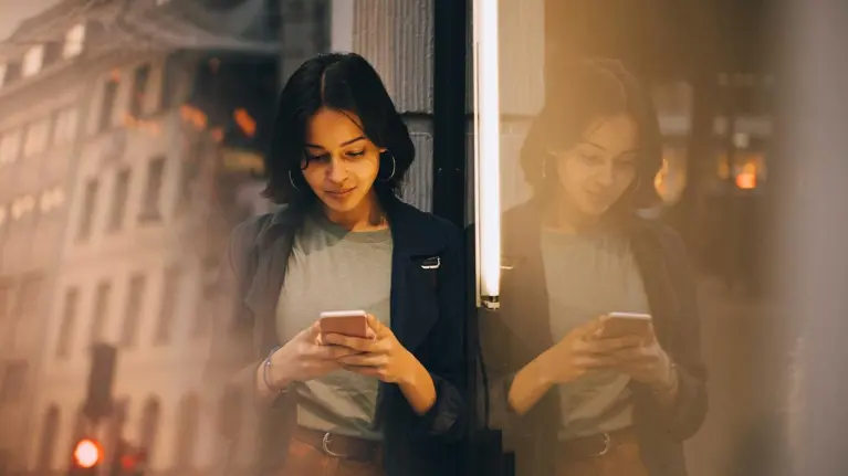 A young woman is using her phone smiling