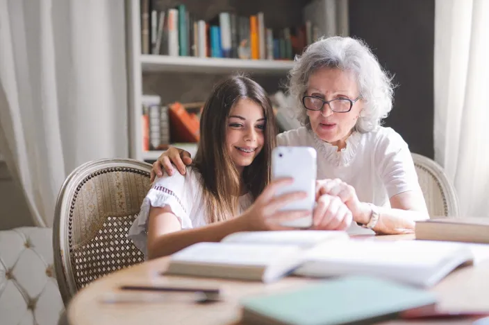 Studying girl showing grandma smartphone