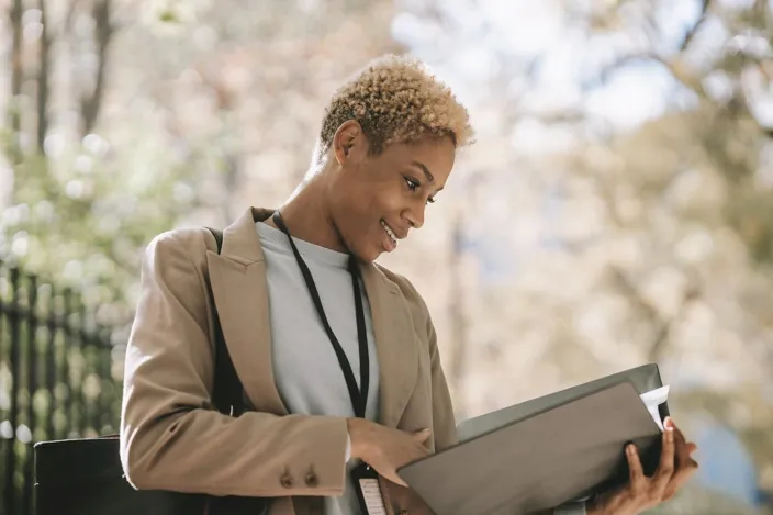 Young woman cheking document folder outside