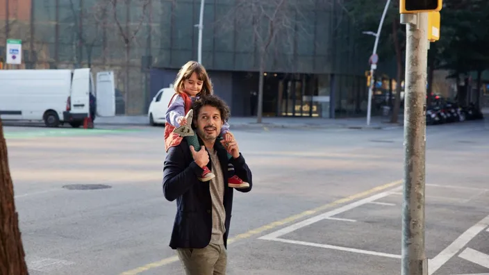 Dad carries his daughter on his sholders in the street environment