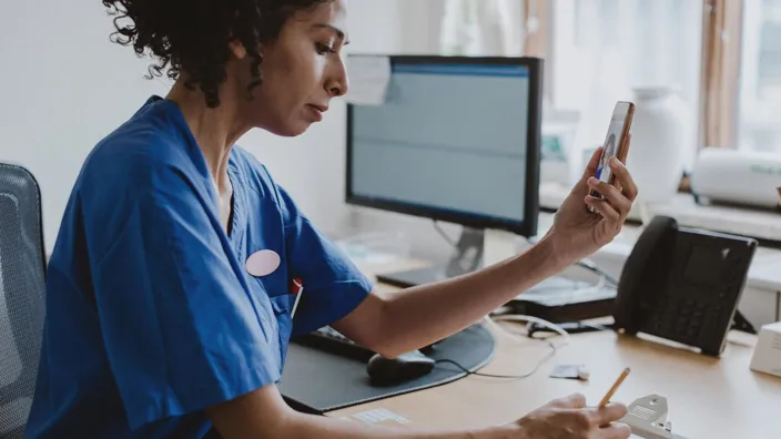 Doctor using a phone, giving patient an online consultation