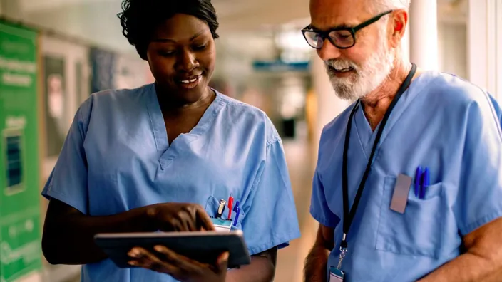 Smiling nurse showing tablet to colleague