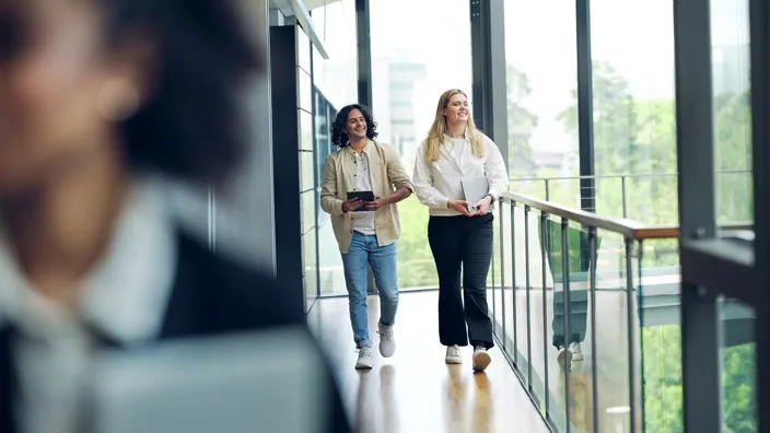 Man and woman walking in Tietoevry office smiling