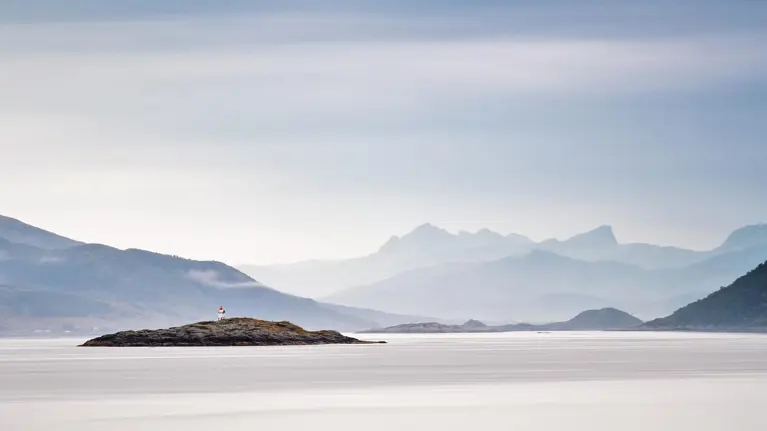 Coast of Norway sea in clouds of haze. Beacon on a rock. Cloudy Nordic day on Lofoten islands