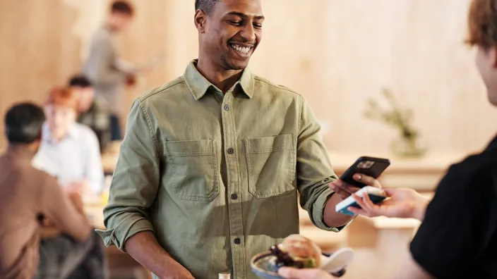 Young man is paying using phone in a small cafeteria