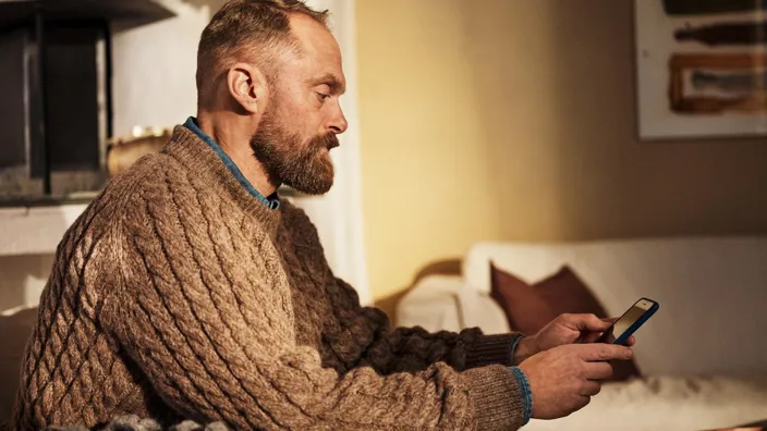 Man using cell phone at home on sofa