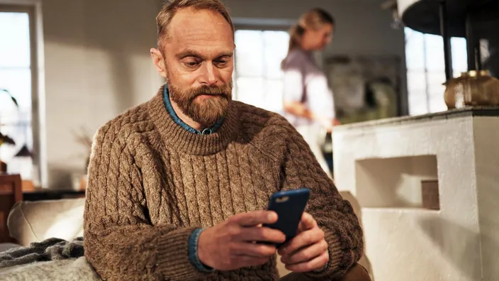 Man using cell phone at home on sofa