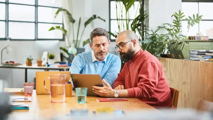 two men looking at computer screen working on a project by the table