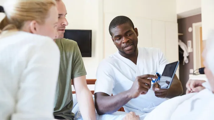 health professional showing patient and his family results of the test on the tablet screen