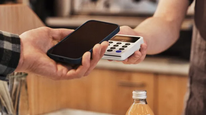 Young man is paying using phone in a small cafeteria