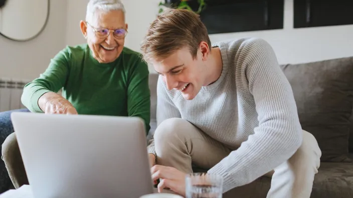 Young man and his grandfather using laptop at home