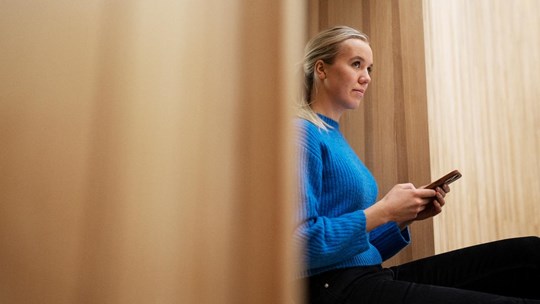 Girl student using phone in public space looking up