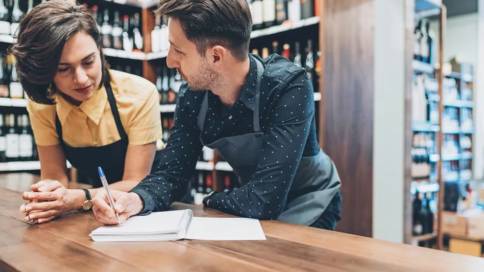 Couple of winery owners talking and writing in a textbook