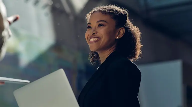 Young woman smiling holding laptop in Tietoevry office