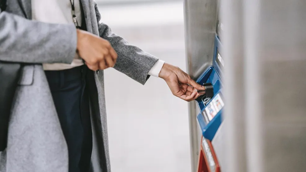 Woman holding a card and using an ATM