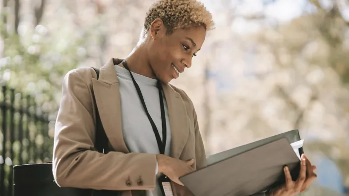 Young woman cheking document folder outside